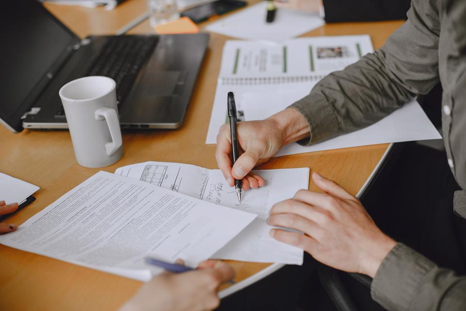 Manos que revisan documentos sobre una mesa.
