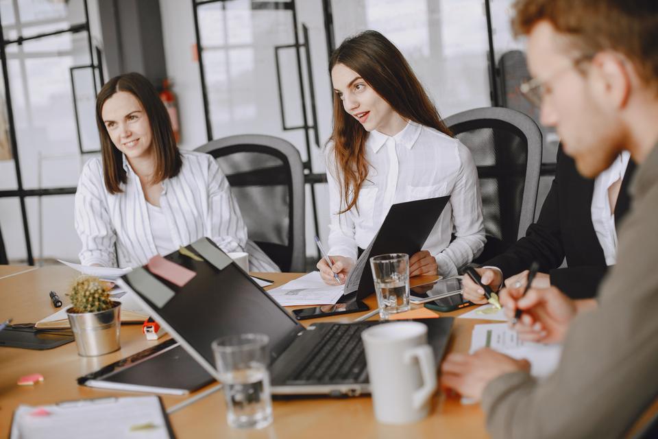 Dos mujeres trabajan con portátiles y dispositivos.
